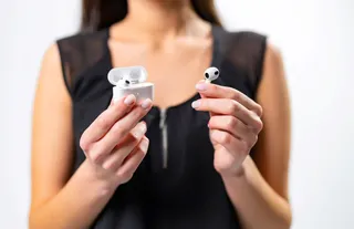Mulher com AirPods na mĂŁo